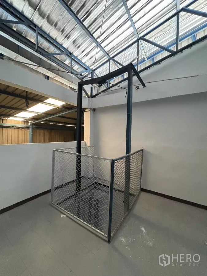 Factory for rent in Khlong Toei, Bangkok - Manual freight hoist platform with safety mesh for moving goods between floors.