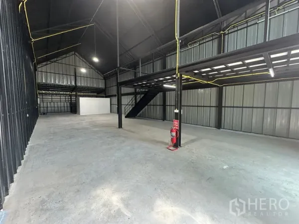 Warehouse for rent in Bueng Kum, Bangkok - Spacious high-ceiling warehouse interior with steel columns, mezzanine platform, and concrete floor.