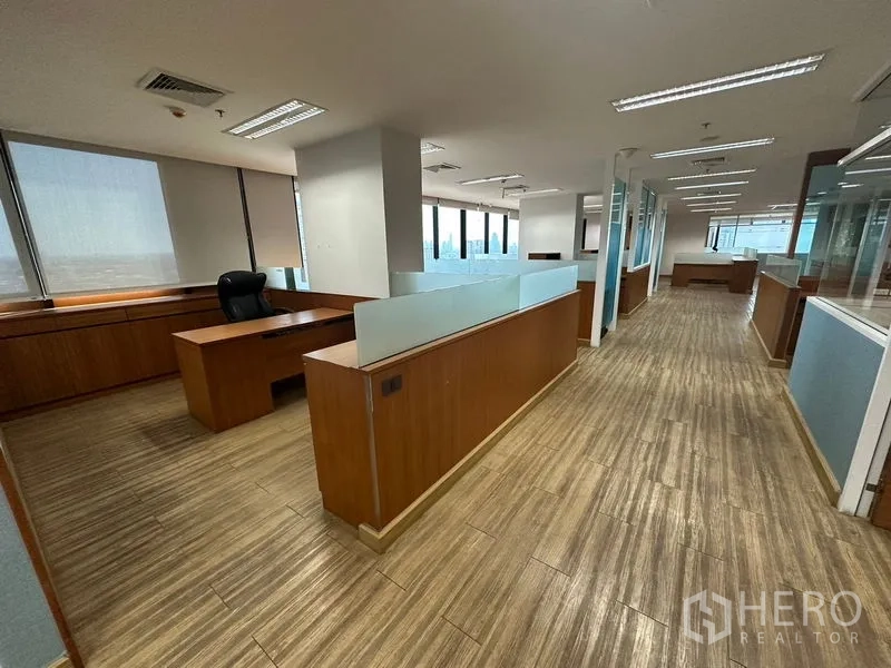 Office Space for rent or sale - Main aisle flanked by cubicles and continuous windows along one side.