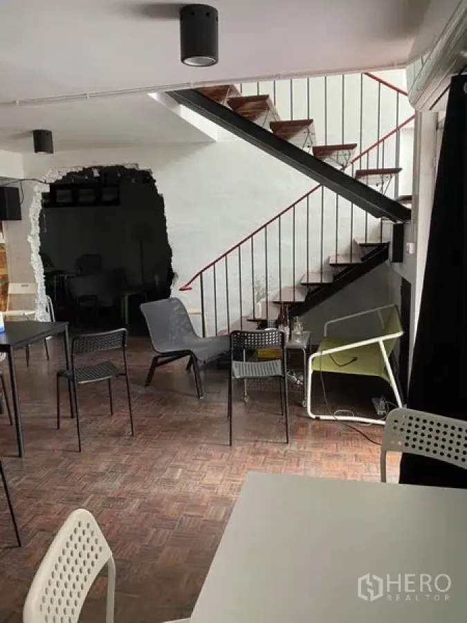 Home Office for rent in Pathum Wan, Bangkok - Open-plan home office with metal staircase, white walls and mixed seating on parquet flooring.