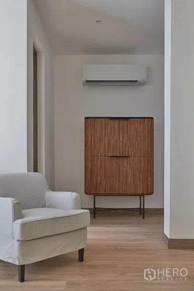 Detached House for rent in Watthana, Bangkok - Hallway nook with armchair, wooden cabinet and wall-mounted air conditioner.