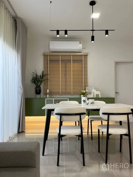 Townhouse for rent in Bang Phli, Samut Prakan - Dining area with modern pendant lights, white chairs, and a green base cabinet with underlighting.