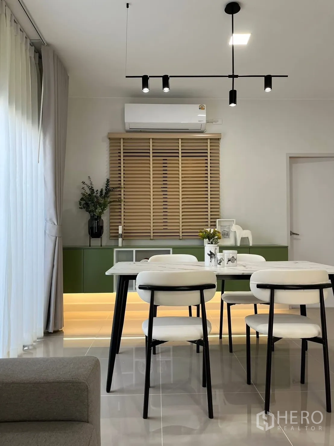 Townhouse for rent in Bang Phli, Samut Prakan - Dining area with modern pendant lights, white chairs, and a green base cabinet with underlighting.