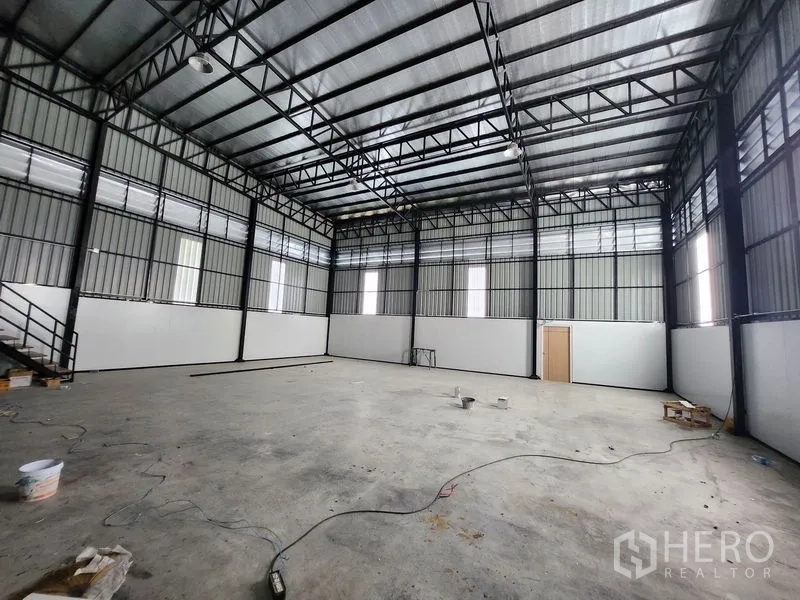 Warehouse for rent in Lam Luk Ka, Pathum Thani - Large empty warehouse hall with high steel truss roof and insulated panels.