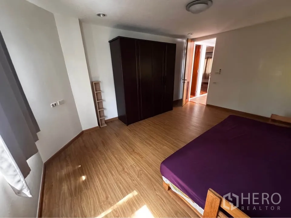 Townhouse for rent in Huai Khwang, Bangkok - Bedroom with wardrobe, wood floors and natural light.