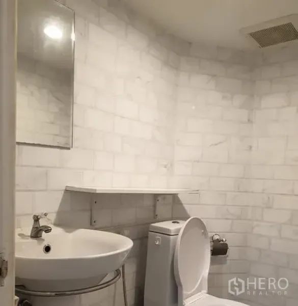 Retail Space for rent in Bang Rak, Bangkok - Modern restroom featuring white marble-look tiles, wall-mounted basin and toilet.