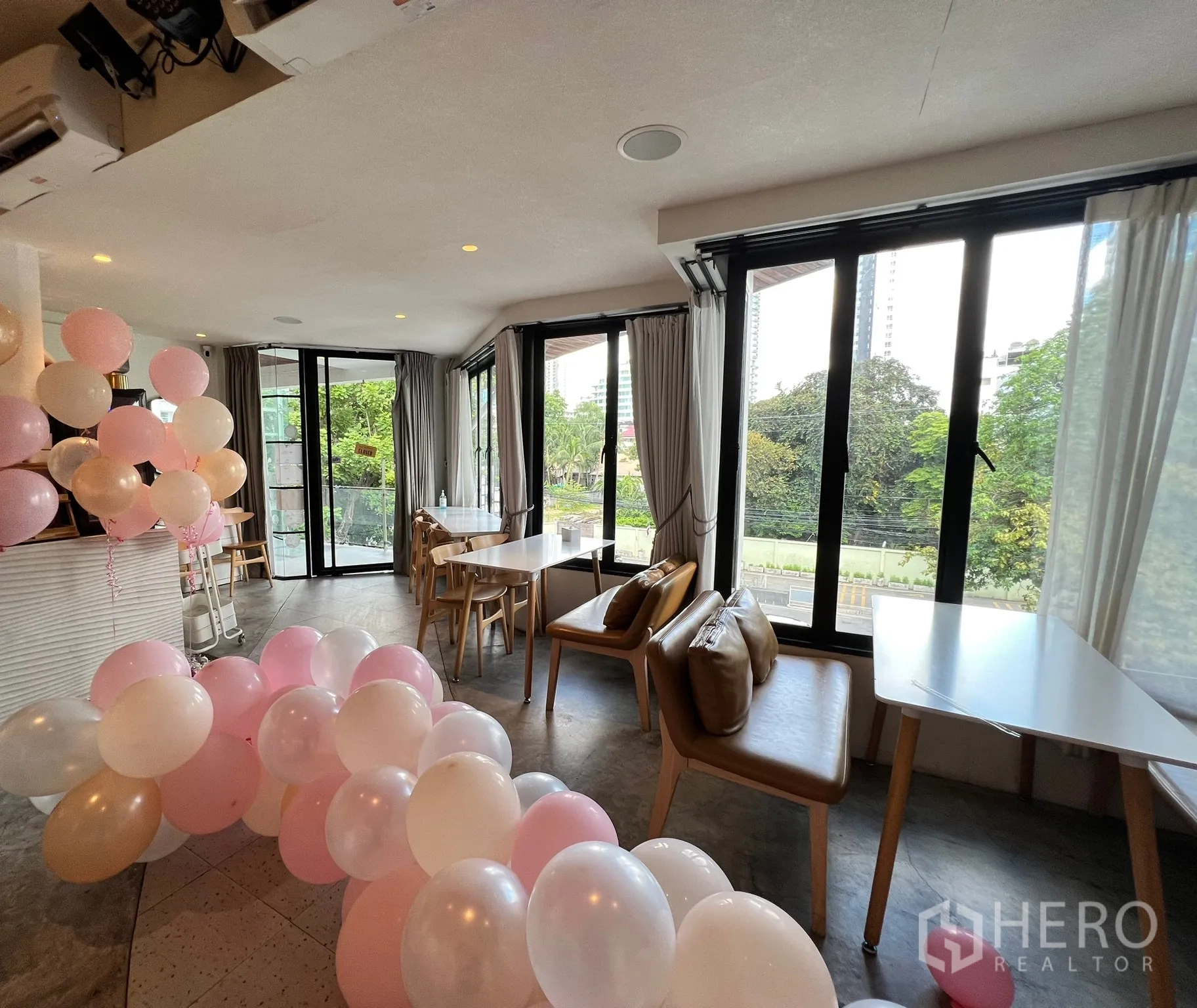 Retail Space for rent in Watthana, Bangkok - Corner seating zone with large windows, natural light and event decor, featuring tables and leather benches.