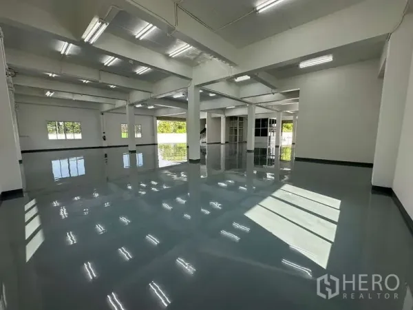 Warehouse for rent in Mueang Samut Prakan, Samut Prakan - Open-plan warehouse interior with reflective floors, skylight windows and a nearby loading area.