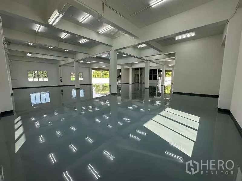 Warehouse for rent in Mueang Samut Prakan, Samut Prakan - Open-plan warehouse interior with reflective floors, skylight windows and a nearby loading area.