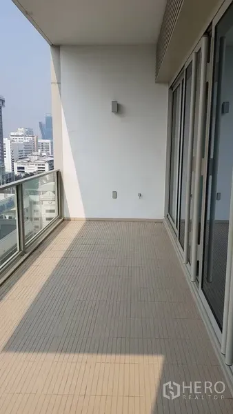 Condominium for rent in Pathum Wan, Bangkok - Spacious covered balcony with glass railing overlooking the Bangkok skyline.