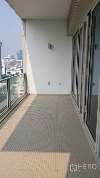 Condominium for rent in Pathum Wan, Bangkok - Spacious covered balcony with glass railing overlooking the Bangkok skyline.