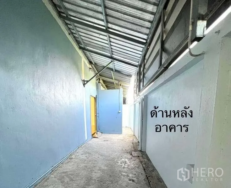 Factory for rent or sale in Mueang Samut Sakhon, Samut Sakhon - Covered rear service corridor along the building with a metal roof.