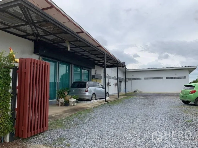 Factory for sale in Bang Pa-in, Phra Nakhon Si Ayutthaya - Low-rise factory exterior with a covered loading bay, glass-front office and gravel parking area.