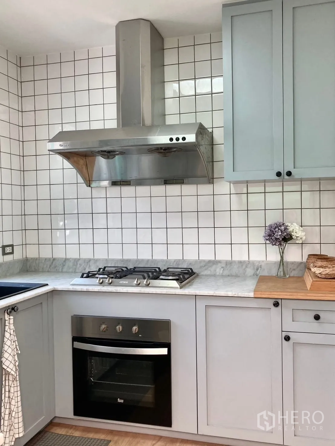 Detached House for rent in Prawet, Bangkok - Close-up of kitchen showing gas cooktop, oven and grey cabinetry.