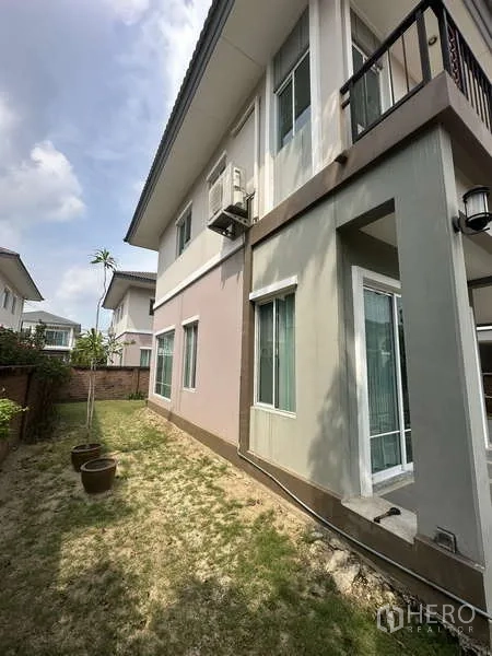 独立式住宅 出售在Sai Mai, Bangkok - 侧院草地与盆栽，带玻璃门的入户口。