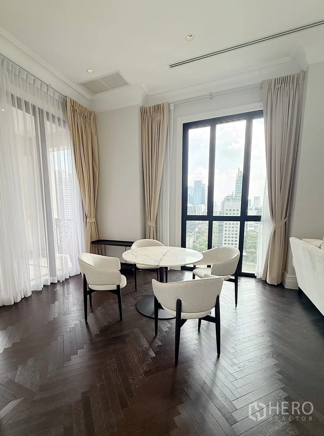 Condominium for rent or sale in Pathum Wan, Bangkok - Dining nook with a round marble table and four chairs next to full-height windows.