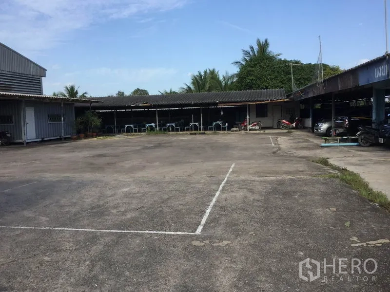 Warehouse for sale in Sai Noi, Nonthaburi - Broad concrete yard surrounded by covered sheds and parking areas.