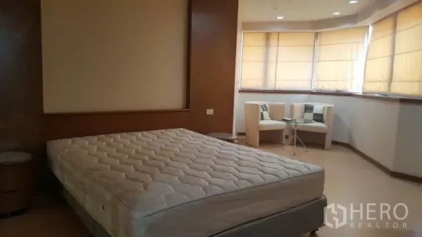 Condominium for rent in Khlong Toei, Bangkok - Master bedroom with king-size bed base, bay-window seating, and warm wood accents.