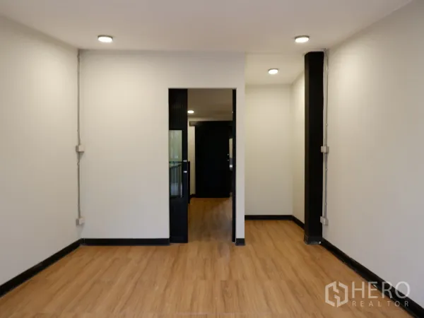 Home Office for sale in Bang Rak, Bangkok - Bright office room with recessed lighting, white walls and a doorway to the service area on wood flooring.