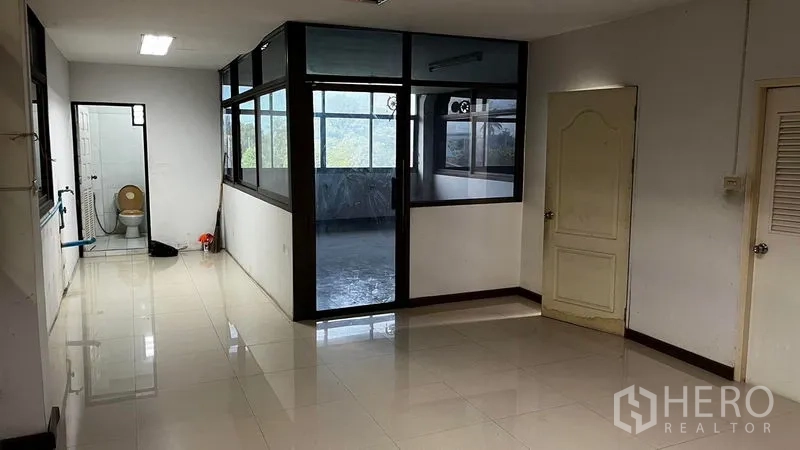 Factory for rent or sale in Pathum Thani - Office space with glass-partitioned rooms, tiled floors and an adjacent bathroom.