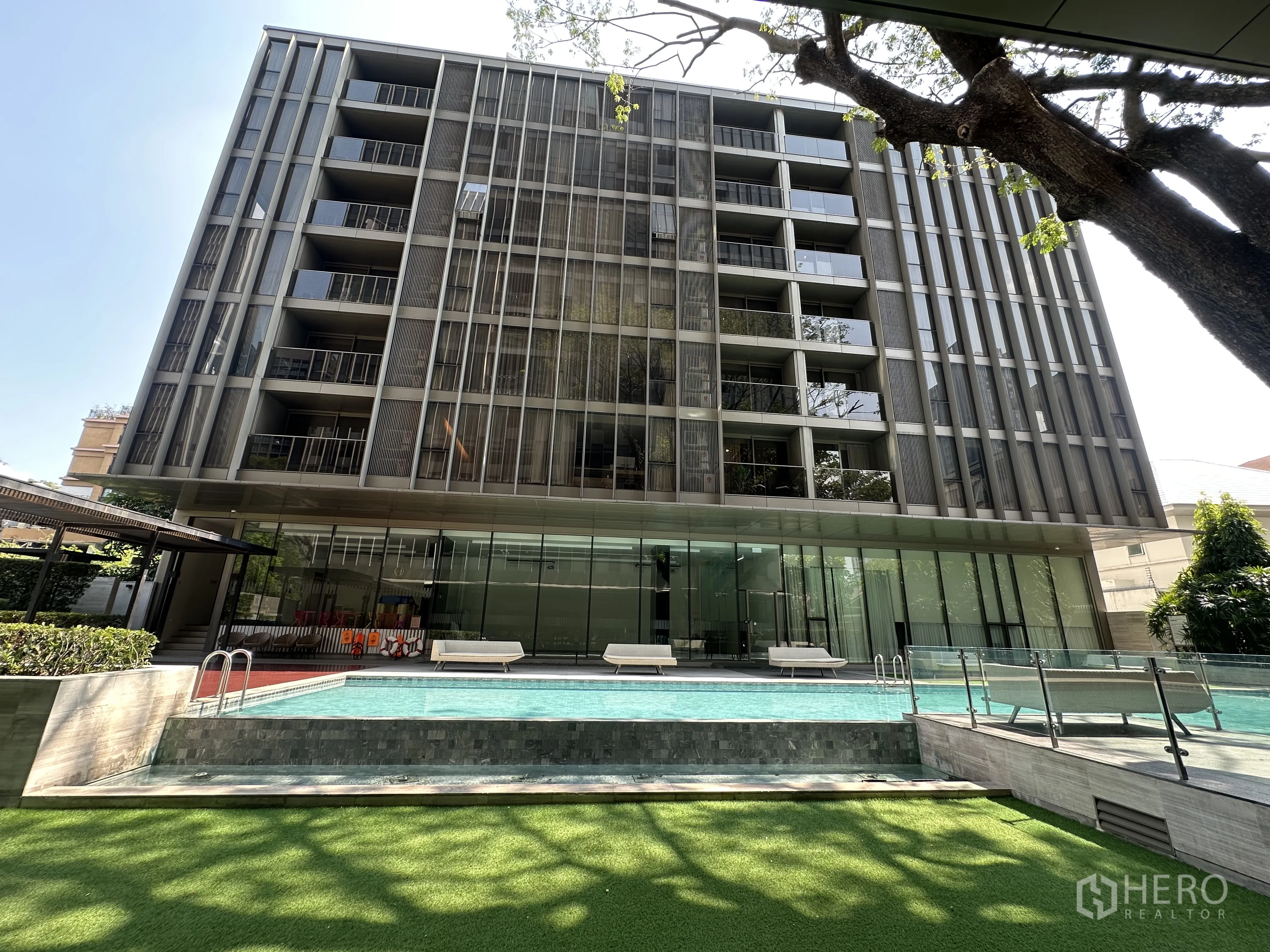 Condominium for rent in Khlong Toei, Bangkok - Modern low-rise condominium exterior with glass facade and swimming pool.