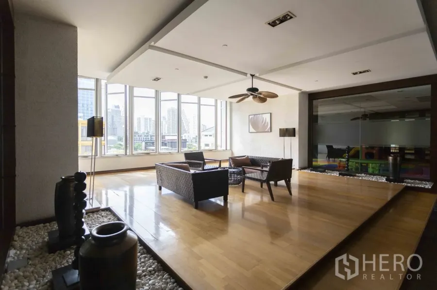 Condominium for rent in Pathum Wan, Bangkok - Condominium residents’ lounge with floor-to-ceiling windows, wood floors and city skyline views.