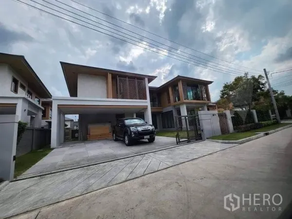 独立式住宅 出售在Sai Mai, Bangkok - 社区街景视角的两层现代别墅，设有庭院大门、车道与车棚。