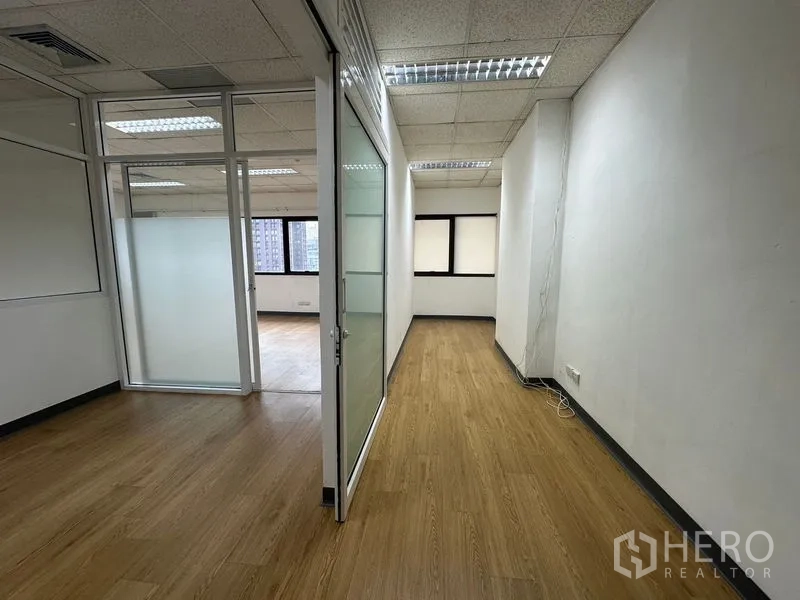 Office Space for rent in Watthana, Bangkok - Hallway leading to a windowed workspace with city views and glass partitions.