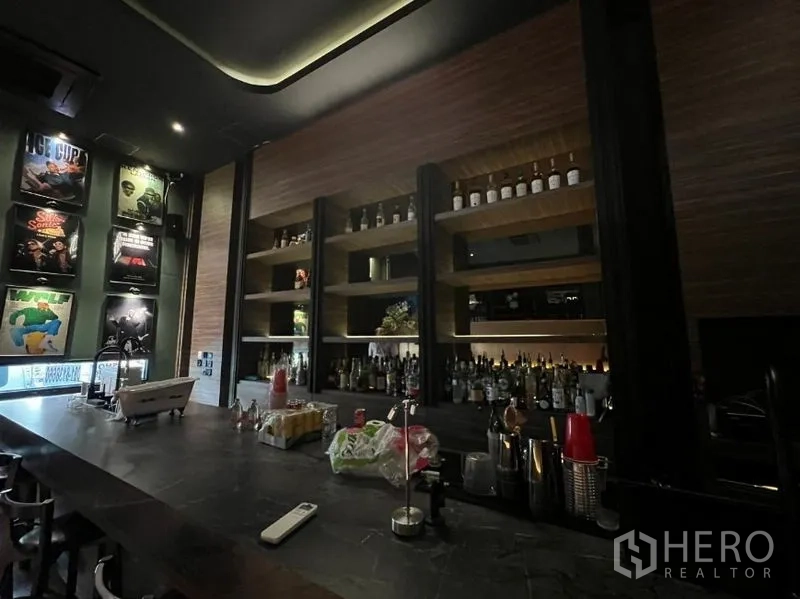 Retail Space for rent in Watthana, Bangkok - Back bar with built-in wooden shelves stocked with bottles and framed posters.