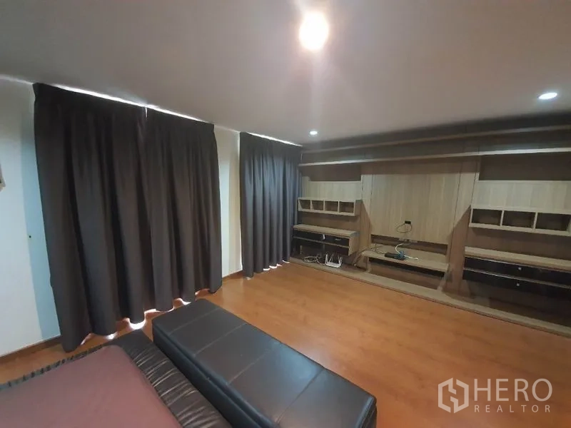 Townhouse for rent in Phaya Thai, Bangkok - Spacious master bedroom with blackout curtains, built-in wood cabinetry and laminate flooring.