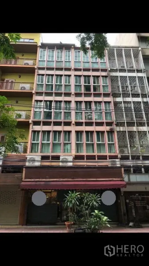 Shophouse for rent in Bang Rak, Bangkok - Multi-storey shophouse facade with large windows, awning and potted plants on a Silom street.