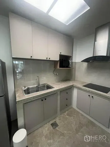Townhouse for rent in Suan Luang, Bangkok - Compact modern kitchen with stone countertops, induction cooktop, hood and upper cabinets.