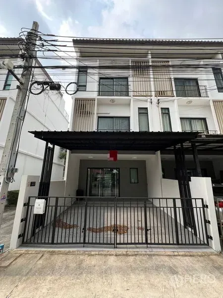 联排别墅 出租在Bang Kapi, Bangkok - 三层现代联排别墅立面，带有遮棚车位与铁门。