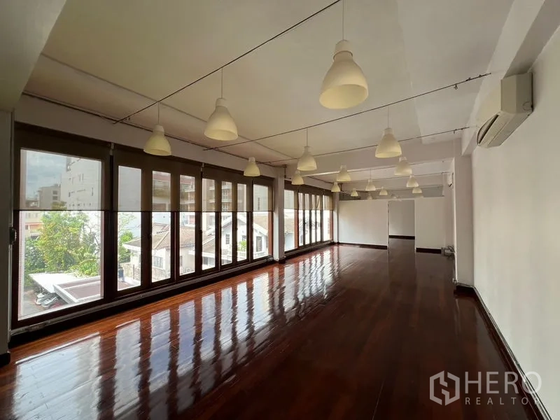 Office Space for rent in Watthana, Bangkok - Open-plan office with polished wooden floors, pendant lights, and full-height windows with district views.