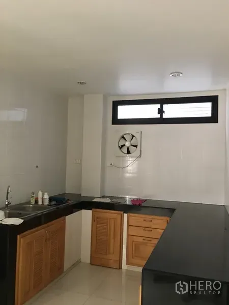 Home Office for rent in Bang Rak, Bangkok - Fitted kitchen with black countertops, wooden cabinets, sink and a wall exhaust fan.
