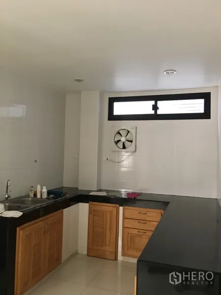 Home Office for rent in Bang Rak, Bangkok - Fitted kitchen with black countertops, wooden cabinets, sink and a wall exhaust fan.