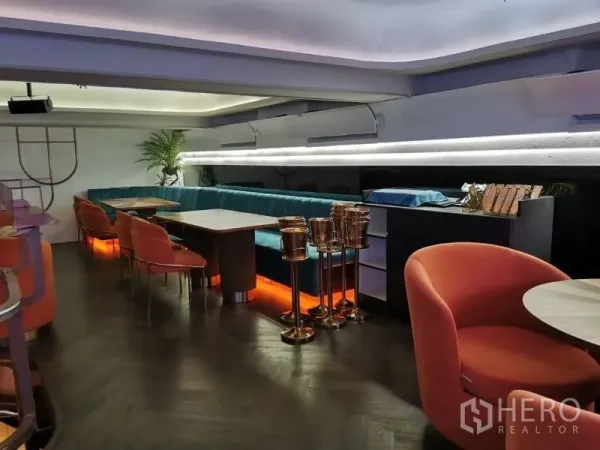 Retail Space for rent - Mezzanine corner with backlit teal bench, orange chairs, and modern ambient lighting.
