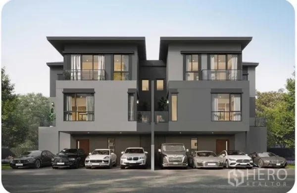 Detached House for sale in Prawet, Bangkok - Contemporary three-storey houses with wide balconies and floor-to-ceiling windows, with multiple cars parked along the front.