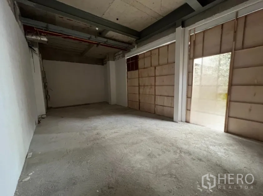 Retail Space for rent in Khlong Toei, Bangkok - Unfinished interior shell with concrete floor and plywood-covered storefront windows.