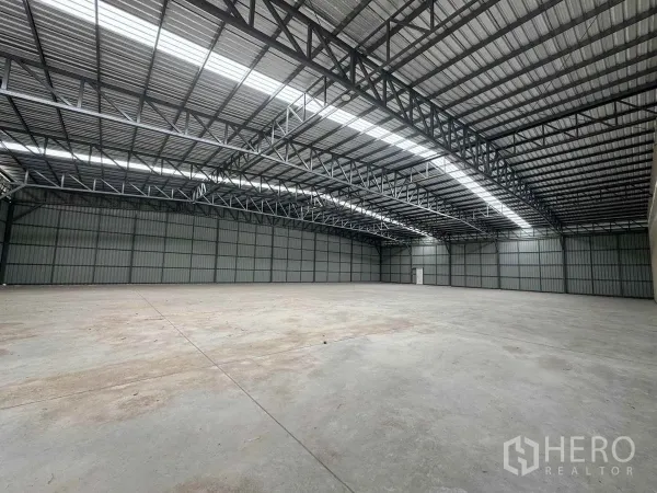 Warehouse for rent in Pak Kret, Nonthaburi - Wide warehouse interior with smooth concrete slab and insulated metal walls.