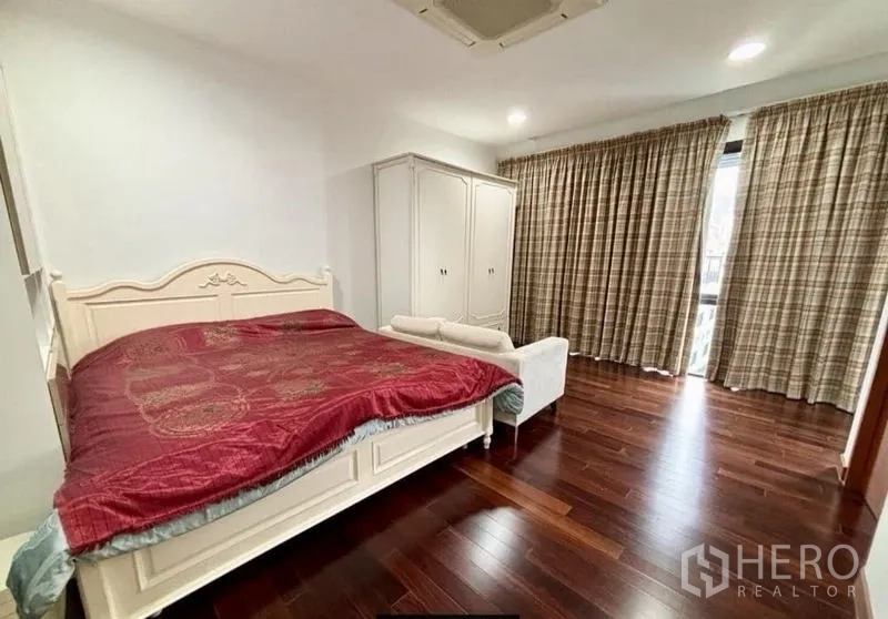 Home Office for rent in Watthana, Bangkok - Spacious bedroom with wooden floors, large bed, wardrobe and full-height curtains.
