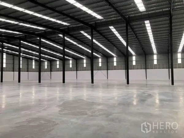 Warehouse for rent or sale in Nikhom Phatthana, Rayong - Industrial hall with rows of black steel columns, skylight panels and expansive clear floor area.
