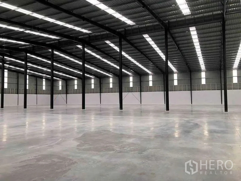 Warehouse for rent or sale in Nikhom Phatthana, Rayong - Industrial hall with rows of black steel columns, skylight panels and expansive clear floor area.