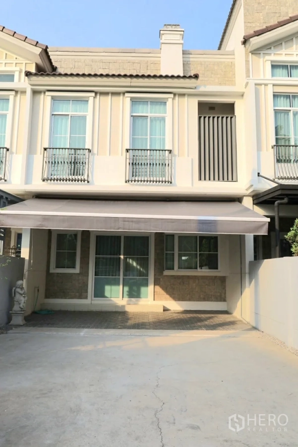 联排别墅 for rent in Prawet, Bangkok - 联排别墅外立面，法式栏杆、遮阳篷与车道车位。