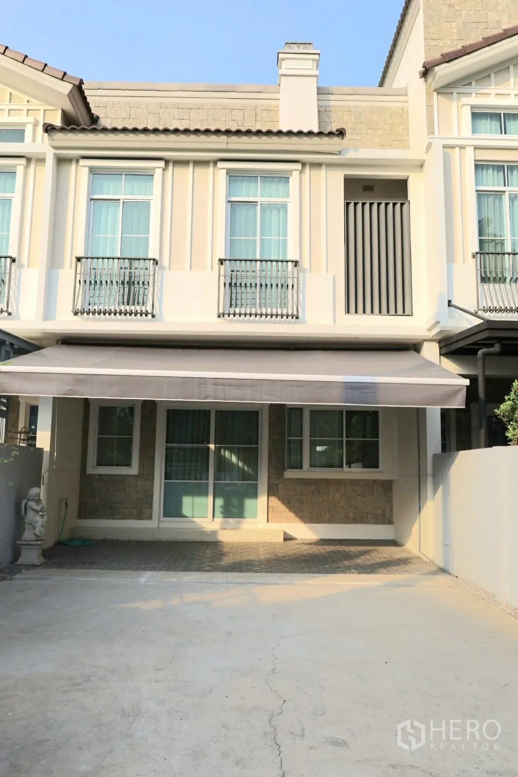 Townhouse for rent in Prawet, Bangkok - Townhouse exterior with classic facade, balcony railings, awning, and driveway parking.