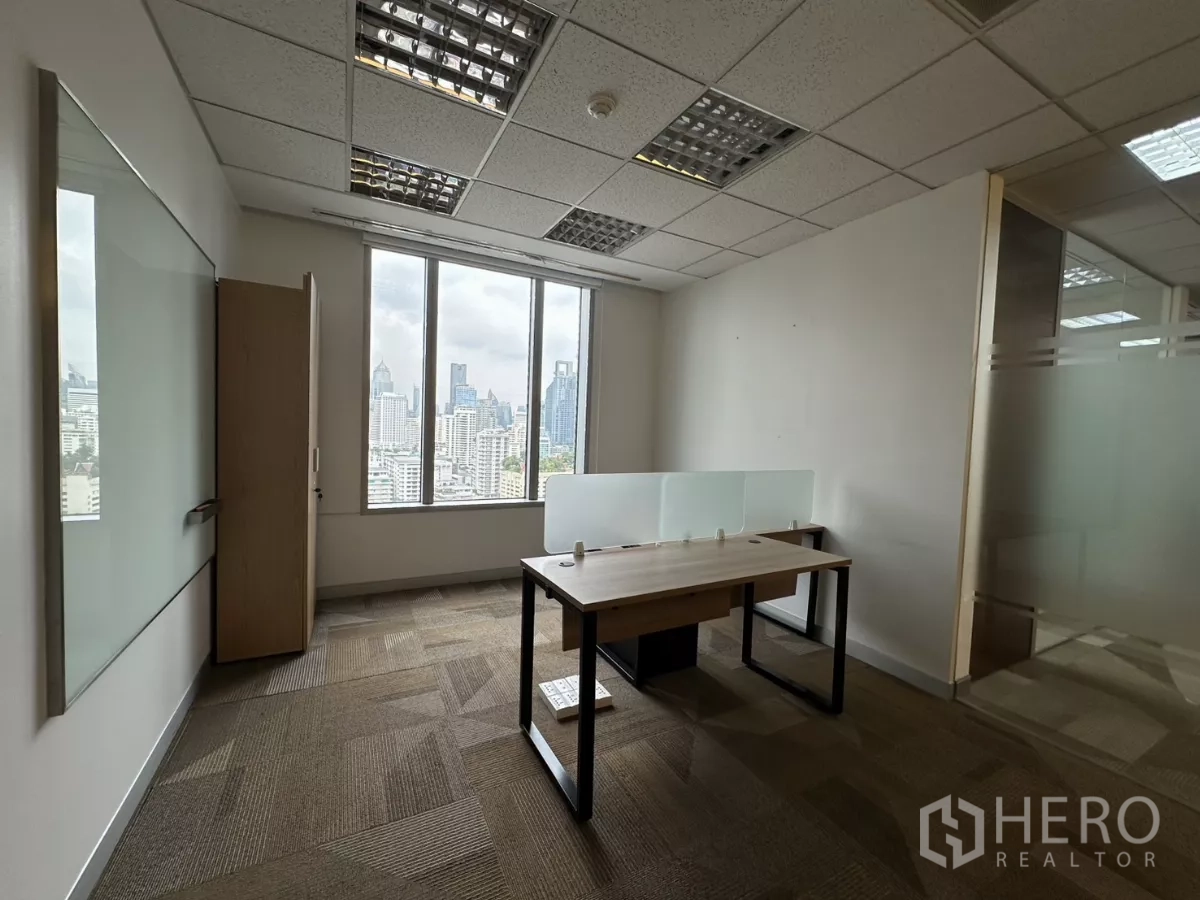 Office Space for rent in Watthana, Bangkok - Private office with a single workstation and floor-to-ceiling city-view window.