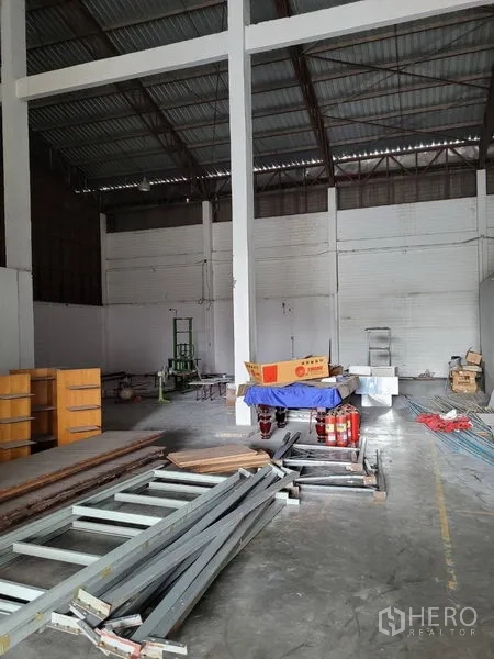 Warehouse for rent in Phra Khanong, Bangkok - Open storage zone in the warehouse showing steel roof trusses and stacked materials.