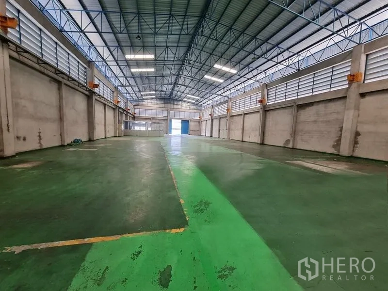 Warehouse for rent in Mueang Samut Prakan, Samut Prakan - Large warehouse interior with green epoxy-marked floor lanes and a ventilated high roof.