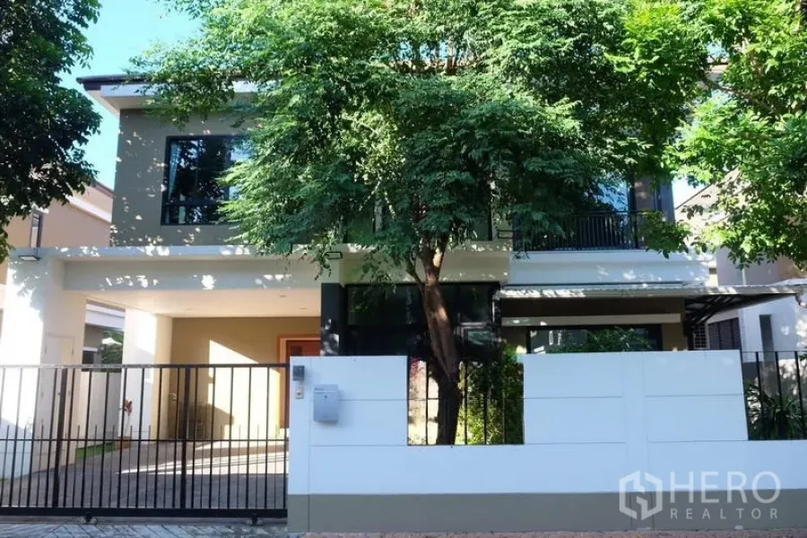 Detached House for rent in Bang Phli, Samut Prakan - Street view of a gated modern detached home shaded by trees.