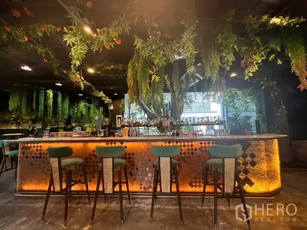Retail Space for rent in Watthana, Bangkok - Warmly lit bar counter with hanging greenery and high stools in a Thonglor retail space.